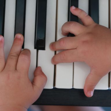 Kindervingers spelen piano, symbool voor speelsheid en verbinding in ouderschap

