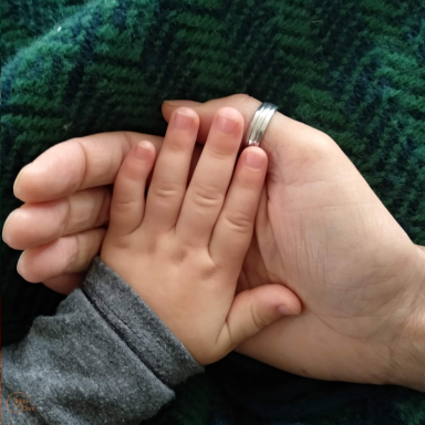 Kinderhand in volwassen hand, symbool voor onvoorwaardelijke aandacht in ouderschap
